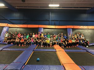 Large Group of Young People Sitting in a Big Trampoline Park